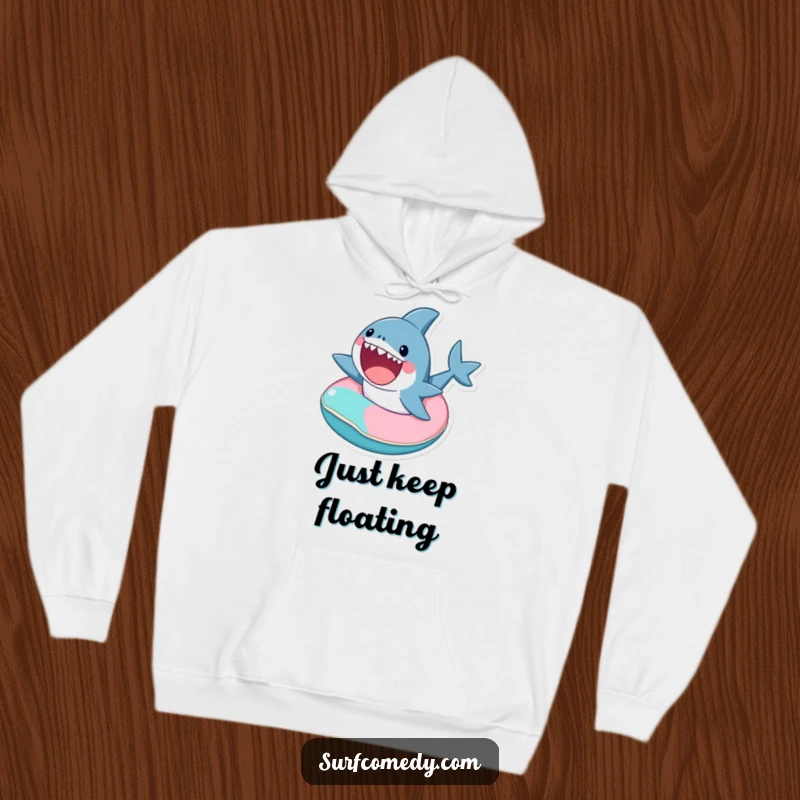 Cozy funny hoodie featuring a cute shark character excitedly riding a tiny, colorful inner tube.